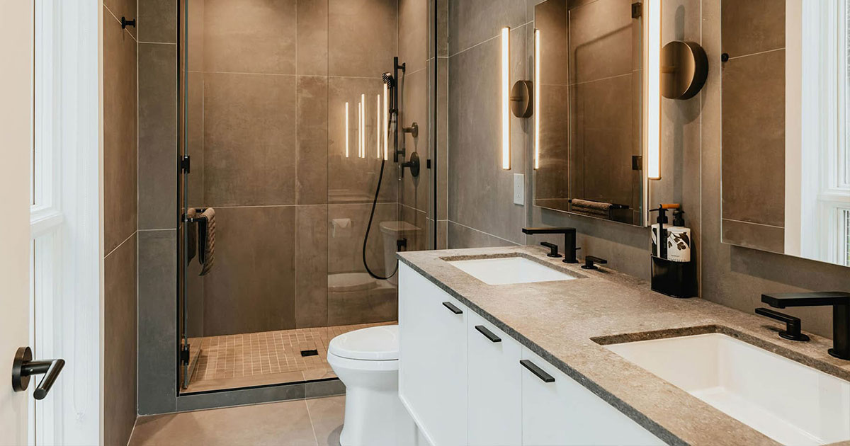 Modern bathroom remodel with large-format tile, glass shower enclosure, double vanity, and black fixtures