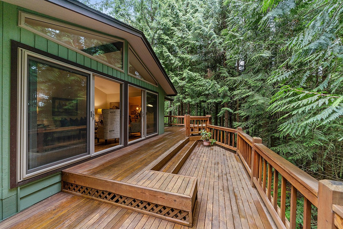 Backyard composite deck with black metal railing and outdoor furniture overlooking a green lawn