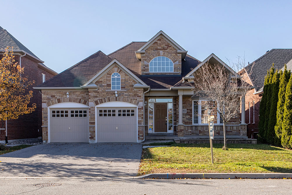Two-story brick and stone home with two tan carriage-style garage doors side by side