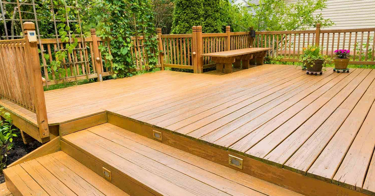 New wood deck with built-in steps, railings, and bench seating surrounded by garden