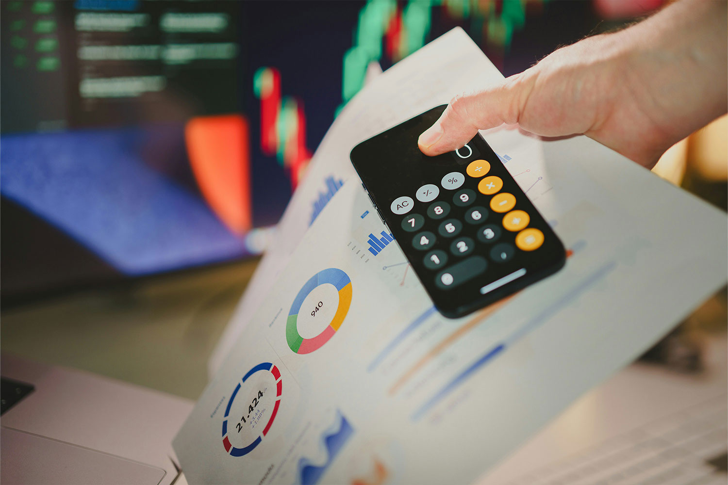 Hand holding a calculator and pie charts