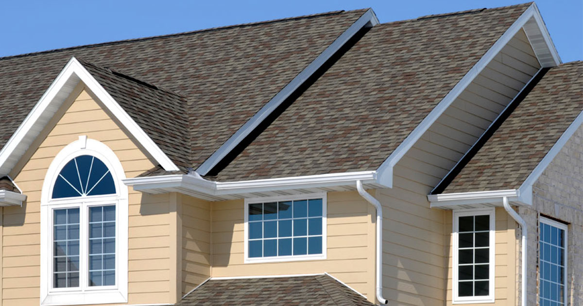 Residential home with new architectural asphalt shingles, gable dormers, and white gutters