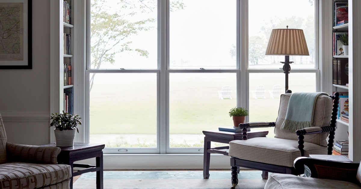 Large double-hung white windows in a residential living room with bookshelves and natural light